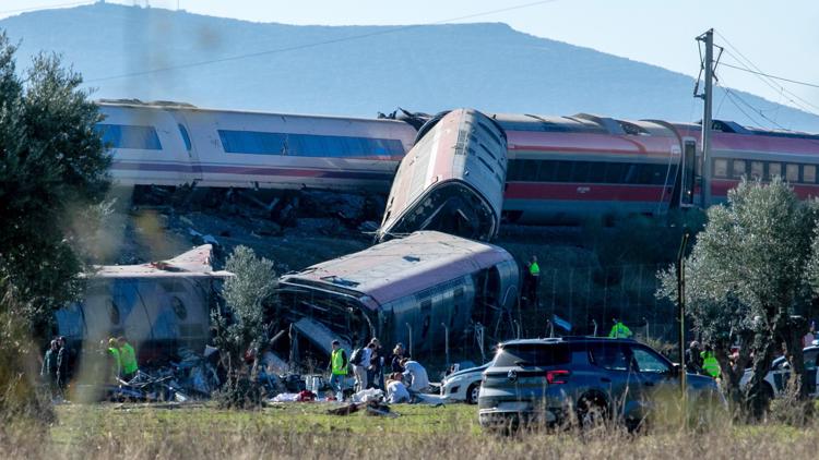 Devastating train crash wreckage in Spain with emergency vehicles and smoke.